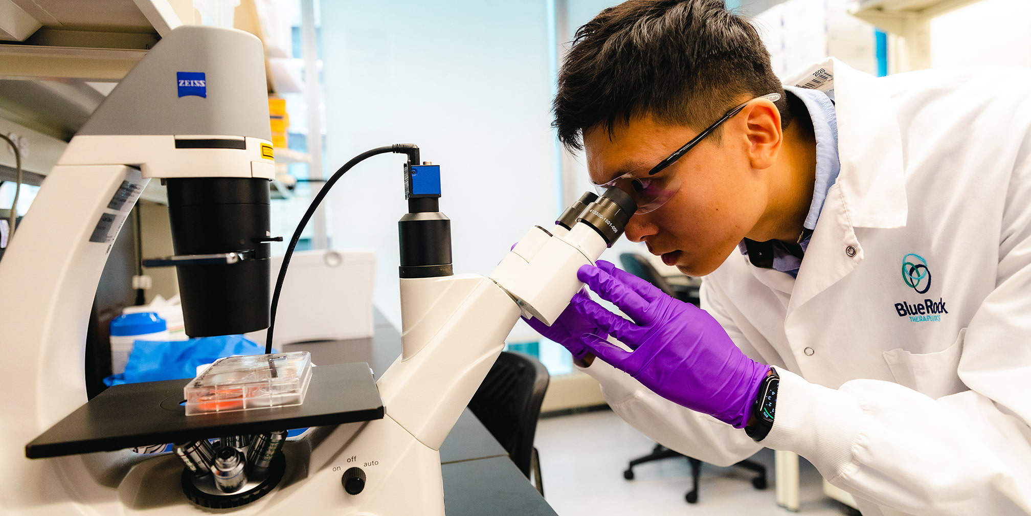 A BlueRock Therapeutics scientist in a lab looking through a microscope